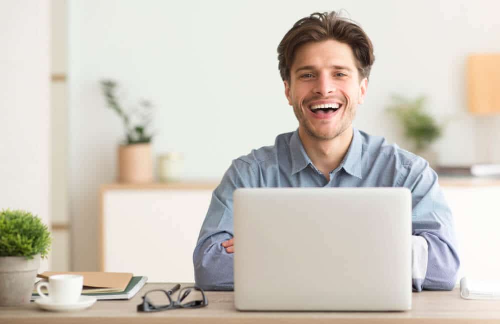 man smiling while working on a laptop