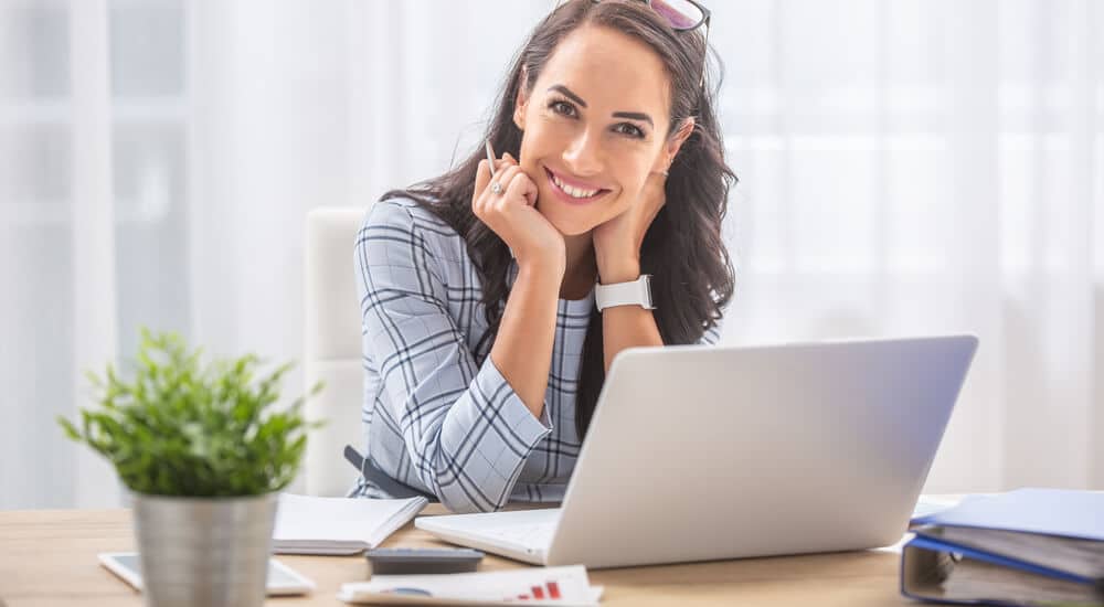 Woman smiling while working on a laptop