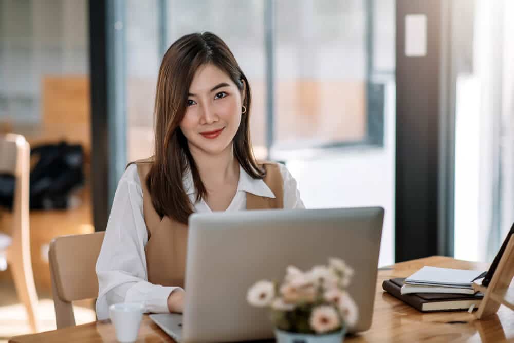 Woman smiling from behind a laptop