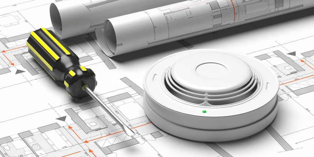 Smoke detector with screwdriver and building blueprints