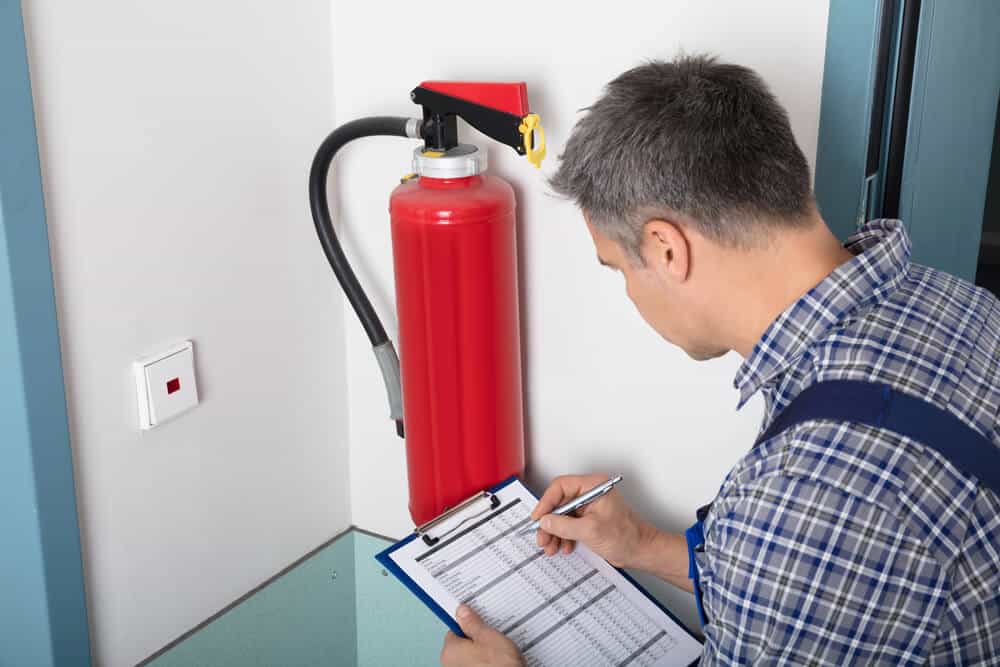 Worker checking list of fire safety equipment