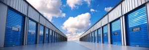 A row of self storage units with blue doors and a clear blue sky above, symbolizing organization, security, convenience, accessibility, and storage solutions.